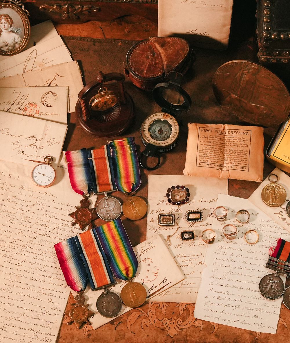 Medals, a pocket watch, rings and letters laid out and photographed from above