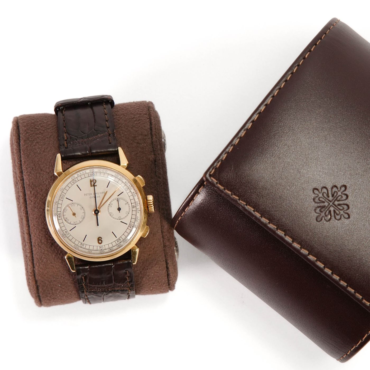 A vintage chronograph wristwatch beside its leather case